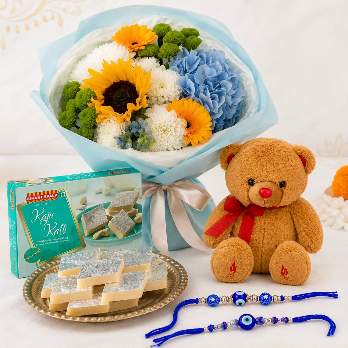 Sunshine Bloom Rakhi hamper with sunflowers, blue hydrangea, kaju katli, teddy and two evil eye rakhis